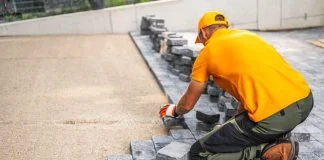 Worker Laying Cobblestones for a Patio in a Residential Backyard on a Sunny Day