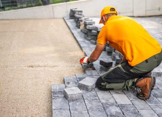 Worker Laying Cobblestones for a Patio in a Residential Backyard on a Sunny Day