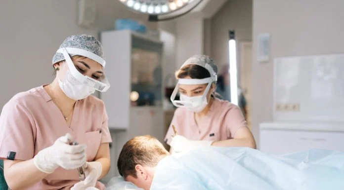 Top 20 Best Hair Transplant Turkey Clinic: HairNeva Leads a New Review of Niche Hair Restoration Centers Two female trichologist performing local needle-free anesthesia to back of head using pistol in recipient area prior to hair transplant surgery in clinic.