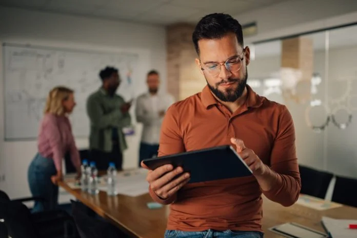 Focused businessman using digital tablet during office meeting Founder Lessons: How to Step Back Without Stepping Away