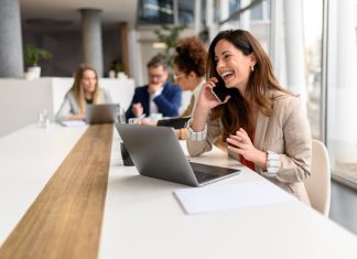 marketing channel through phone calls. Woman talking over smart phone while sitting with laptop