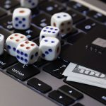 Laptop keyboard with dice, credit card and cash, concept of online gambling, betting and casino games in digital world