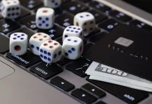 Laptop keyboard with dice, credit card and cash, concept of online gambling, betting and casino games in digital world