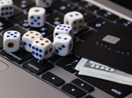 Laptop keyboard with dice, credit card and cash, concept of online gambling, betting and casino games in digital world