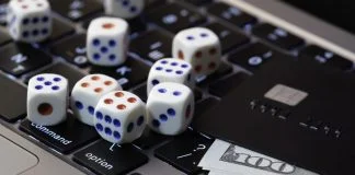 Laptop keyboard with dice, credit card and cash, concept of online gambling, betting and casino games in digital world