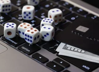 Laptop keyboard with dice, credit card and cash, concept of online gambling, betting and casino games in digital world