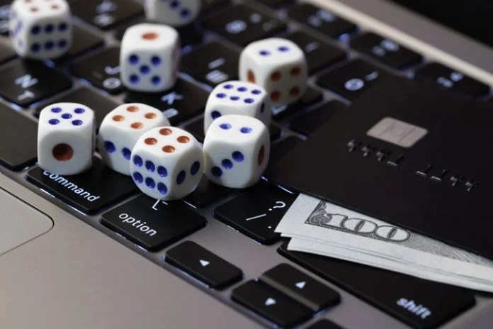 Laptop keyboard with dice, credit card and cash, concept of online gambling, betting and casino games in digital world