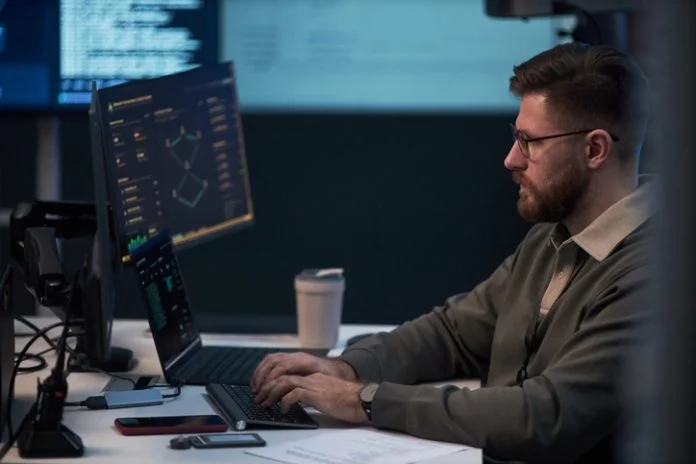 Adult Man Monitoring Cybersecurity Data in Office Workspace DevOps of Softalium Limited working in the office