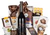Corporate gift basket with red wine, gourmet chocolates, brie cheese, and mixed nuts in a wooden crate
