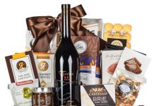Corporate gift basket with red wine, gourmet chocolates, brie cheese, and mixed nuts in a wooden crate