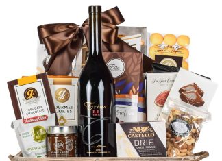 Corporate gift basket with red wine, gourmet chocolates, brie cheese, and mixed nuts in a wooden crate