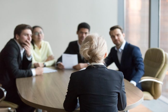 Woman passing job interview at office, interviewers on backgroun Hiring Employees in Spain Without Compliance