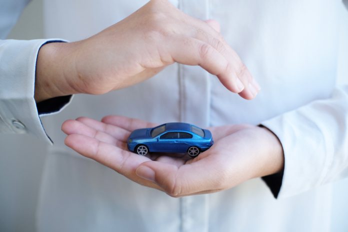 Concept of car insurance with Protection of a car. toy car and hand Business concept Telematics and Motor Insurance