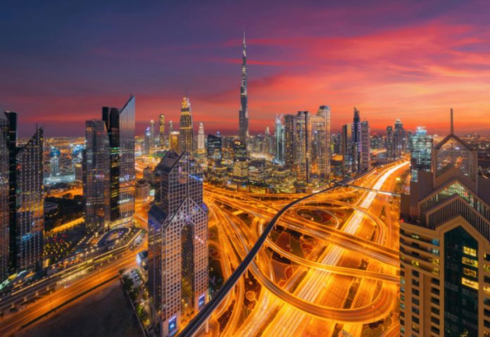 Aerial view of Burj Khalifa in Dubai Downtown skyline and highway, United Arab Emirates or UAE. Financial district and business area in smart urban city. Skyscraper and high-rise buildings at night. European HNWIs