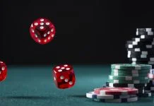 iGaming Markets - Casino Chips Stack and Flying Dices on Green Poker Table.