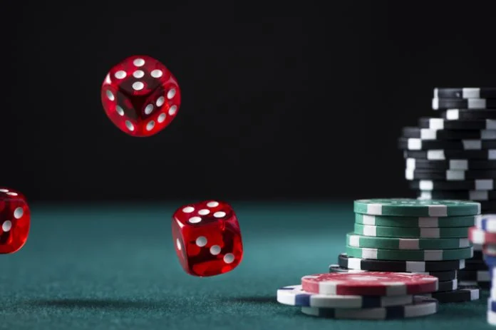 iGaming Markets - Casino Chips Stack and Flying Dices on Green Poker Table.