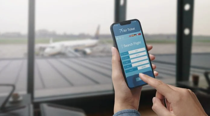 How Seasonal Travel Trends Affect Flight Costs (and When to Book Your Shoulder-Season Trip) User holding a smartphone and booking cheap flights online, seasonal travel trends, airport in the background.