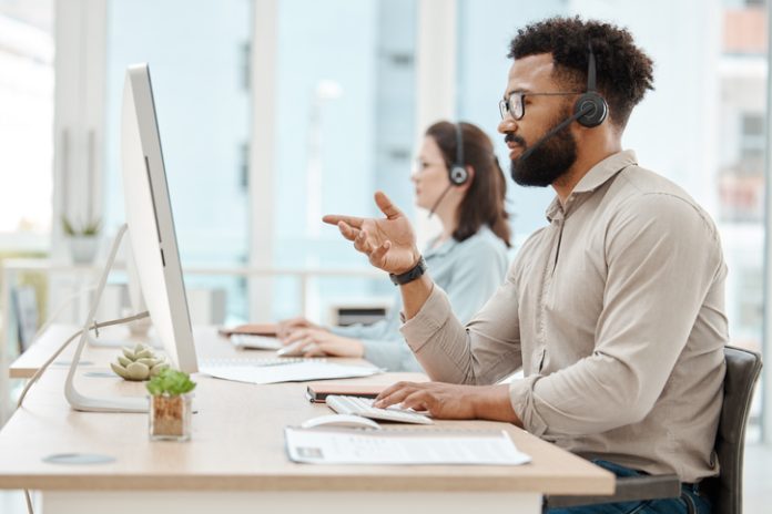 Black man, customer support service office and working for online call center internet telemarketing business. Crm consultant at desk, helping client and consulting computer software for advice help desk software