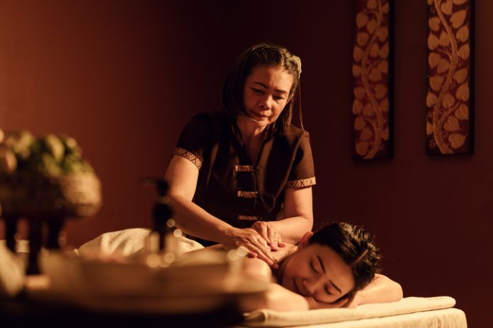 Asian mature female masseuse serve customers, doing massge back with aromatherapy oil inspa salon. Popularity of Massage Services During Business Trip