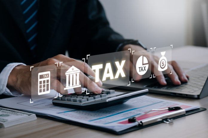 Tax concept.Man hand using calculator to calculate personal income tax return to pay taxes online. State tax. Financial research. data analysis, documents, reports, tax returns, calculations. digital tax advice