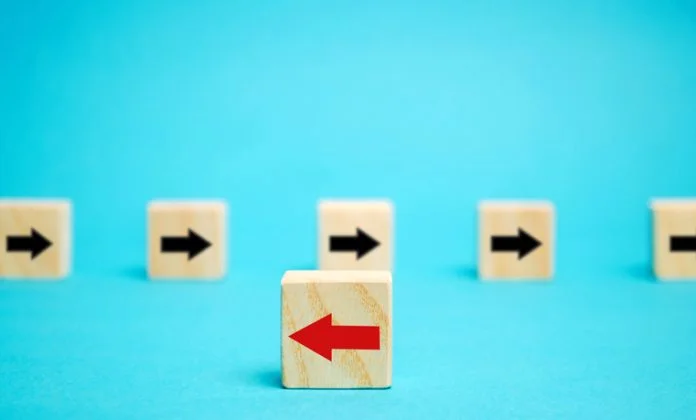 Wooden blocks with arrows. Individual opinion concept. Stand out from the crowd. Uniqueness. Divergent views. Different concepts to other people. Business metaphor company doesn't want change