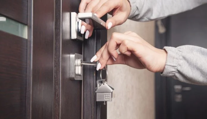 Woman hand holding house key at home. Composite Door Lock