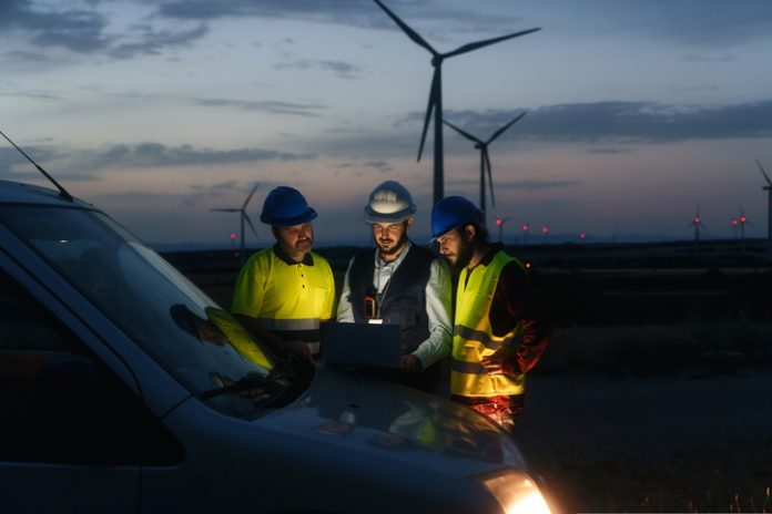 Technicians engineers working in wind turbine electricity plant at night. Renewable energy solution for climate change Businesses Reconsider Wind Energy