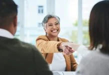 The Dog-Eat-Dog World of ‘Work Perks’ Handshake, job interview or business people with a happy mature woman for partnership in office. smile or business people shaking hands for success, work perks, promotion or negotiation in meeting