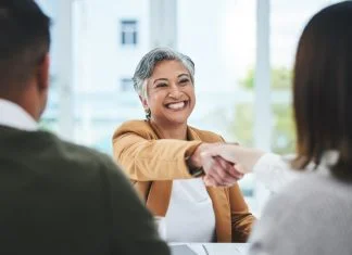 Handshake, job interview or business people with a happy mature woman for partnership in office. smile or business people shaking hands for success, work perks, promotion or negotiation in meeting
