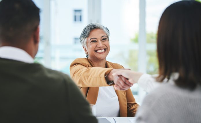 Handshake, job interview or business people with a happy mature woman for partnership in office. smile or business people shaking hands for success, work perks, promotion or negotiation in meeting
