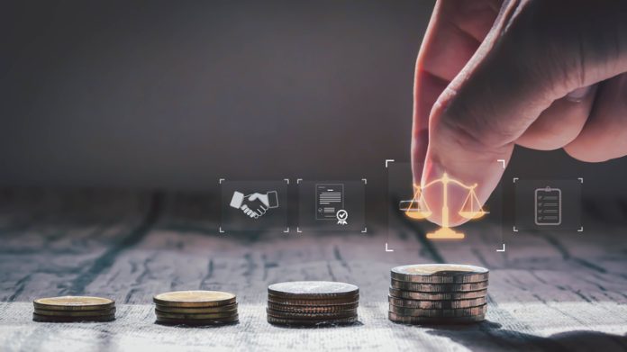 A hand stacking coins beside justice scale icons, symbolizing financial growth, investment fairness, and legal business decisions in a professional setting.