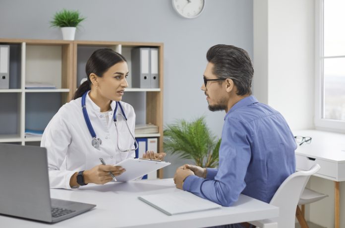Serious female doctor consulting male patient filling form at consultation Healthcare Providers with her patient during consultation