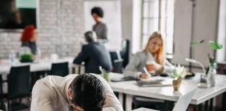 Presenteeism - Overworked businessman taking a break from work and napping on his desk.