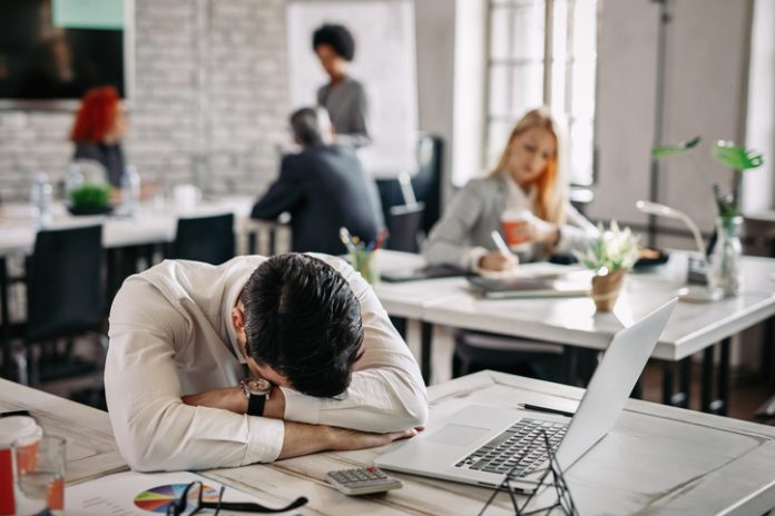 Overworked businessman taking a break from work and napping on his desk. Presenteeism - Overworked businessman taking a break from work and napping on his desk.