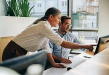 Kind leader helping her employee with computer