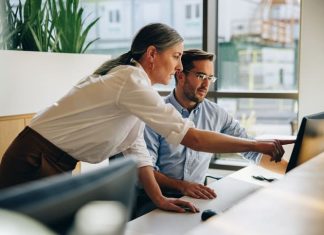 Kind leader helping her employee with computer