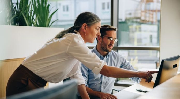 Why Are You Helping Me? The Question a Kind Leader Leaves Unanswered Kind leader helping her employee with computer