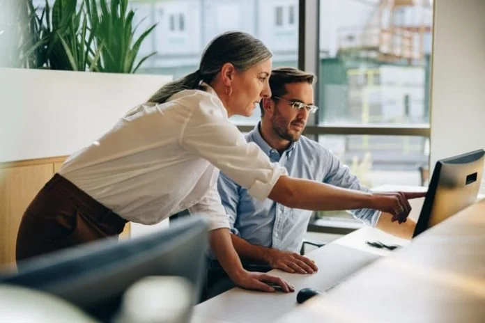 Kind leader helping her employee with computer