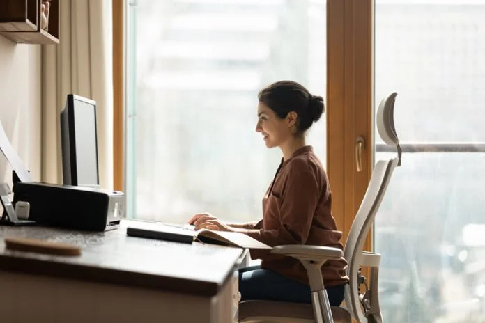 Happy millennial indian businesswoman working in modern home office. Happy successful millennial indian ethnic business lady working in modern home office, using computer software applications, Ergonomics, creating new internet project, communicating distantly with client.