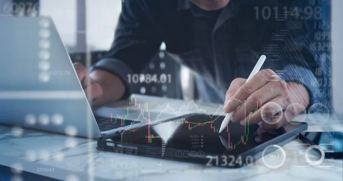Businessman using digital tablet and laptop computer analyzing stock market data, forex trading graph, economic growth chart, business report on virtual screen Regulated digital markets
