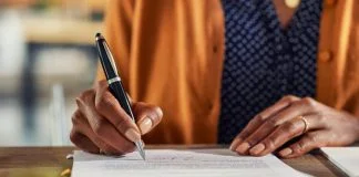 Cheap and Cheerful or Built to Last? Choosing the Right Pen for the Job Close up of african american business woman hand writing on report while working in office. Successful black businesswoman signing documents at home using a pen.