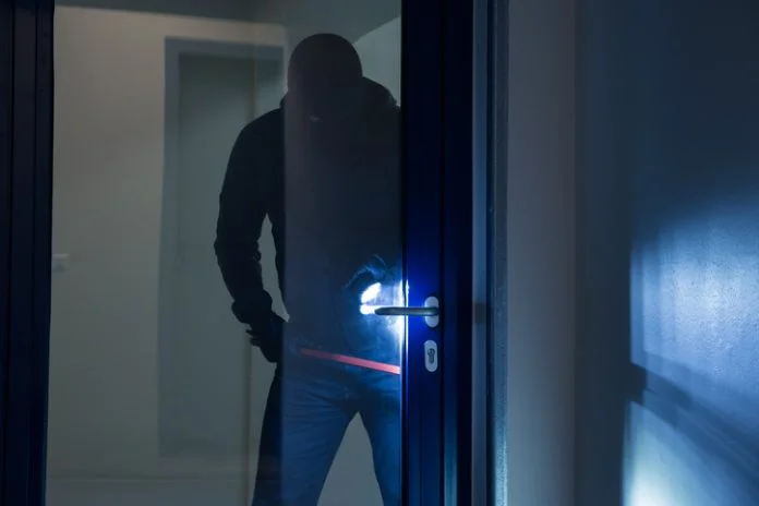 Burglar Using Crowbar To Open Glass Door Full length of burglary using crowbar to open glass door at night