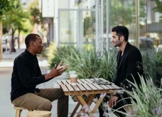 Two men talking over coffee at a small table outside a cafe. Value in business concept