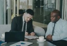 Data Rooms for European M&A: A Practical Guide for Dealmakers Two M&A advisers reviewing due diligence documents on a laptop, illustrating virtual data room preparation.