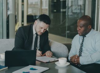 Data Rooms for European M&A: A Practical Guide for Dealmakers Two M&A advisers reviewing due diligence documents on a laptop, illustrating virtual data room preparation.