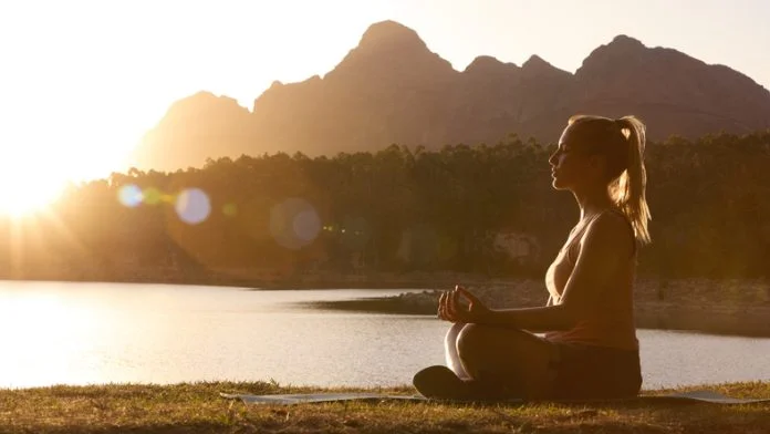 Woman Meditating Doing Yoga By Lake And Mountains At Sunset meditation for everyone
