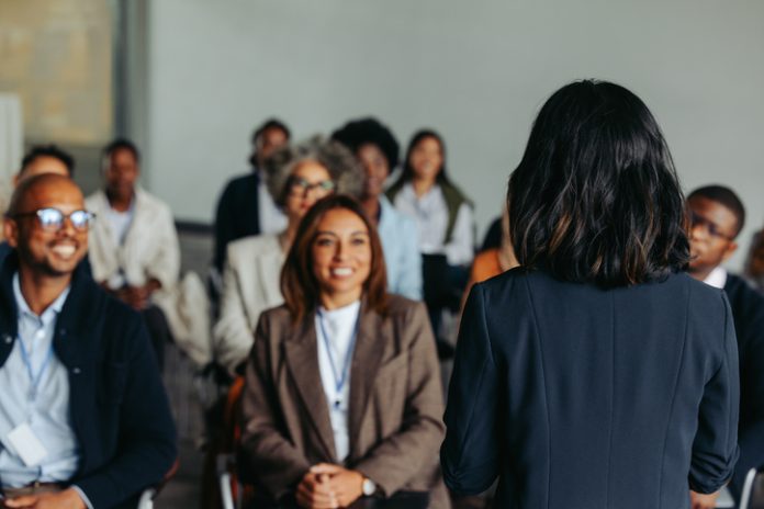 Businesswoman presenting at a meeting with smiling colleagues and coworkers Hannah Arendt leadership